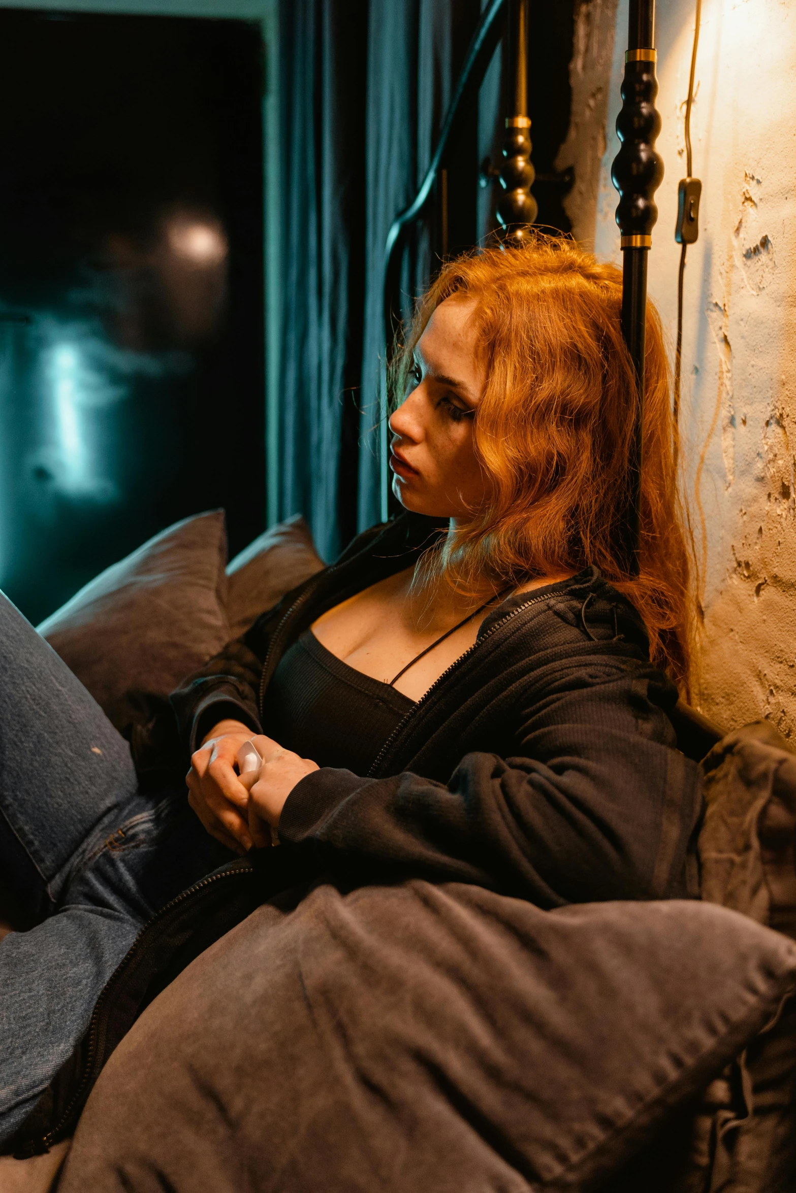 a red - haired woman rests on a bed and stares at the screen