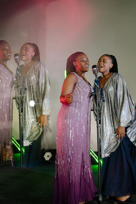 two female entertainers singing into microphone with three singing girls standing behind them