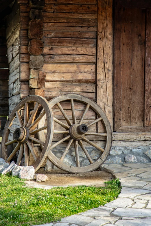 an old wagon wheels sits outside a log cabin