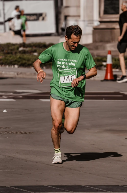 a man in a green shirt and white shorts is running on the road