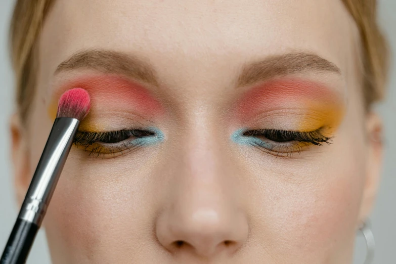 a woman with makeup and some oranges on her eyes