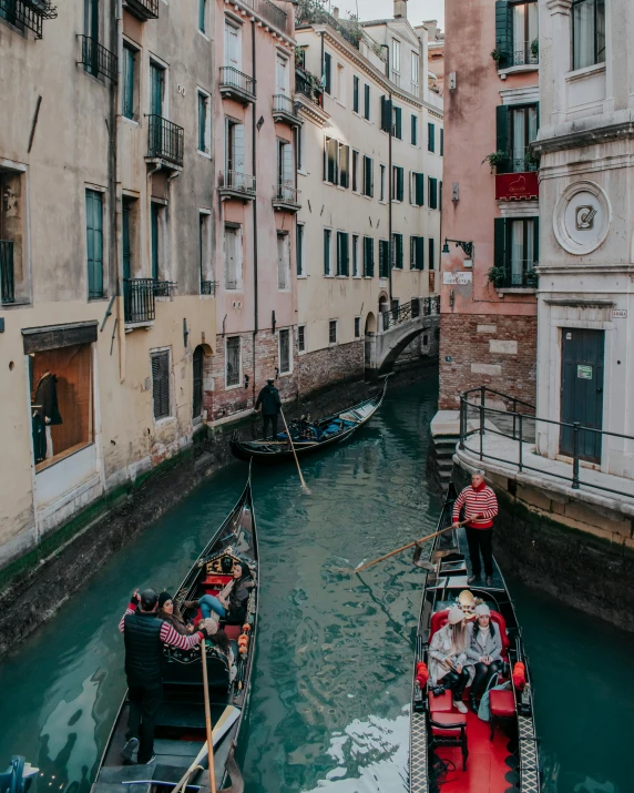 two people sitting on their boat and another person walking along side of the water