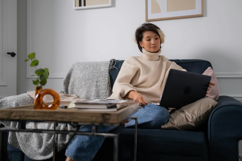 a person sitting on a couch while holding a laptop