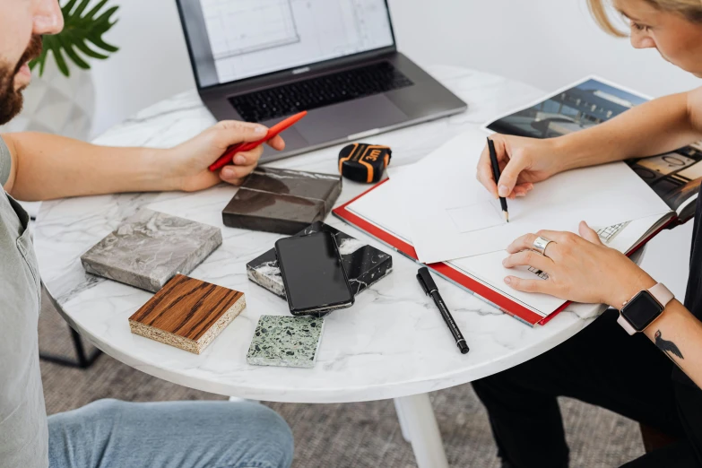 two people are working with various stationary items on a round table