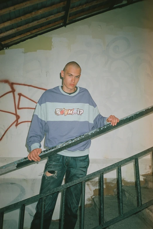 a man wearing a striped shirt and jeans holds onto railing