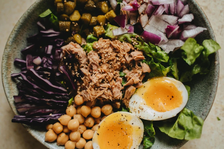 bowl filled with meat, vegetables, eggs and two kinds of salad