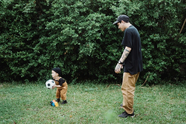 a father and son are standing in the grass with a ball
