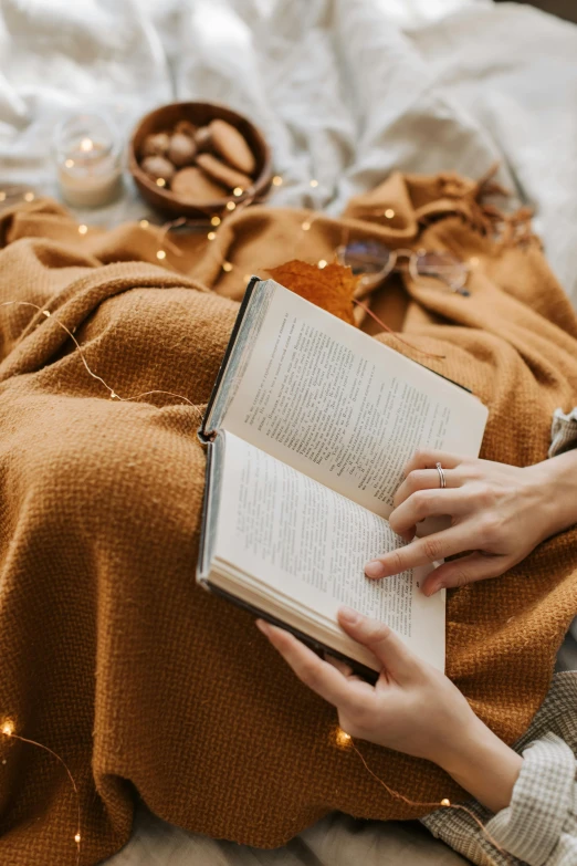 a person laying on a bed reading a book