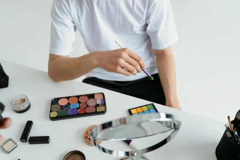 a man sitting at a table in front of makeup