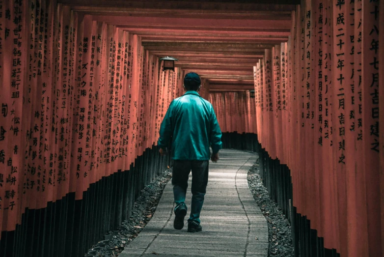 man walking down pathway lined with red wall