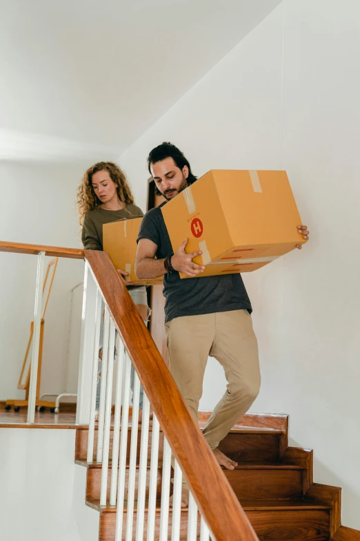 a man and a woman standing on the stairs of a house while moving boxes