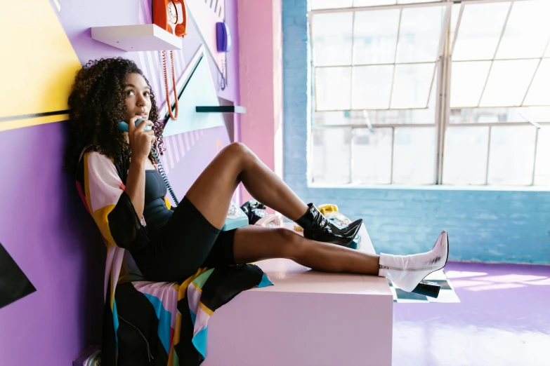 a woman with bright colors sits on the edge of a wall