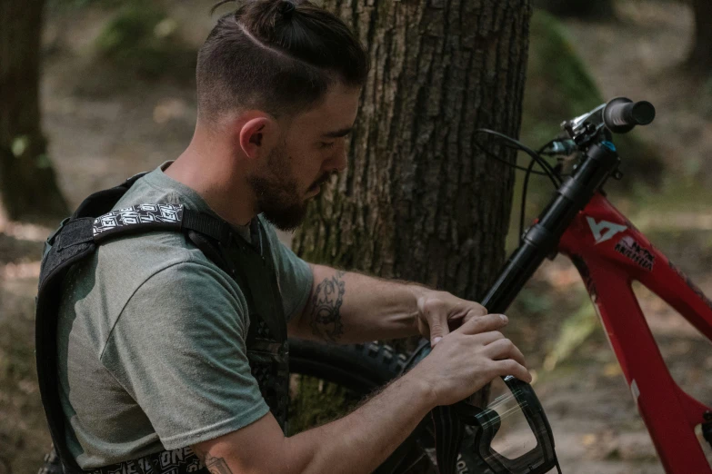 a young man working on his bike in the woods