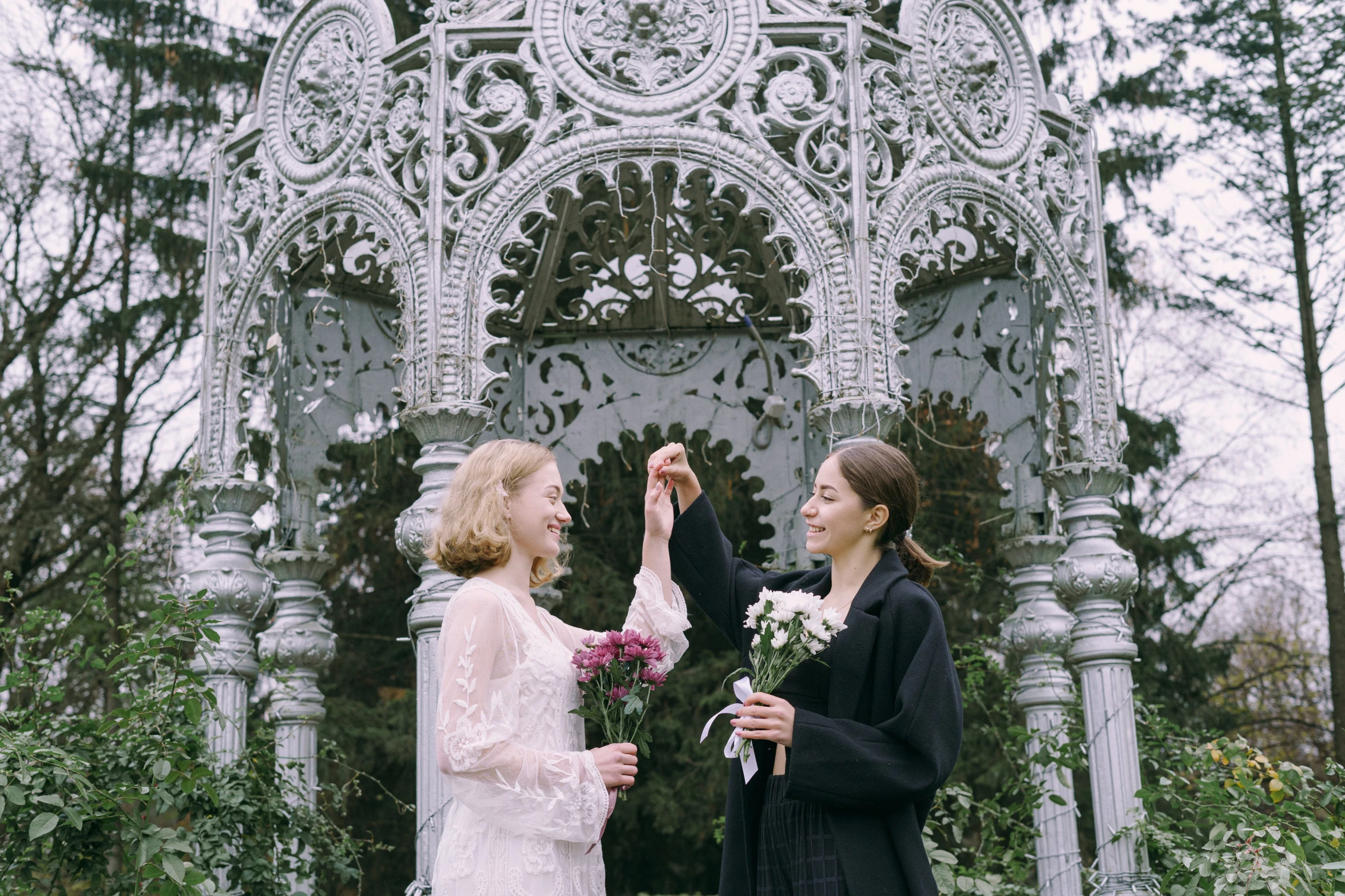 two women holding each other's hand at an outdoor ceremony