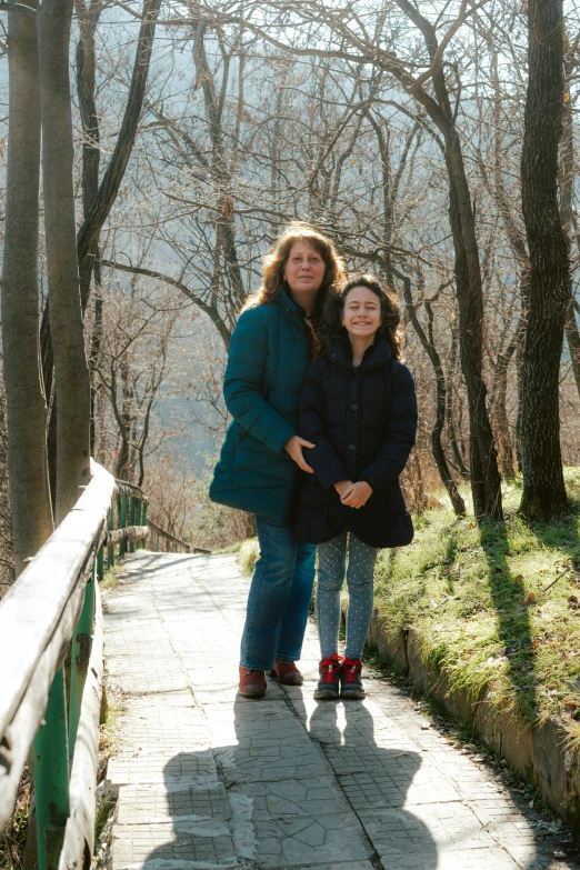 two people are hugging while standing on a bridge