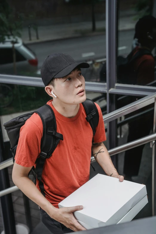 young man with a black cap holding two boxes