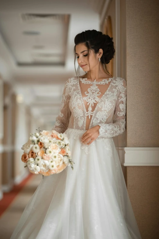 a woman holding a bouquet of flowers and wearing a white wedding gown