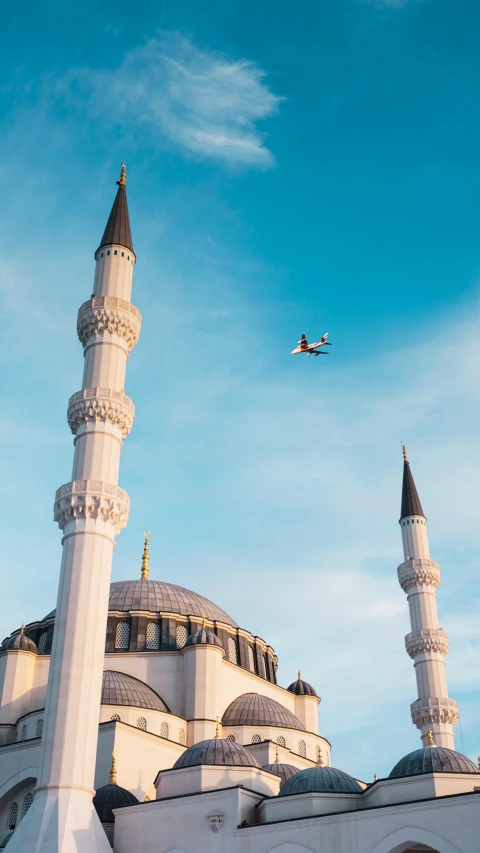 an airplane flying over a white building with a plane overhead