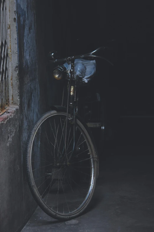 a bicycle sitting in the dark next to the wall