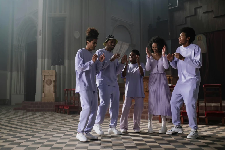 six people in white outfits stand together and clap