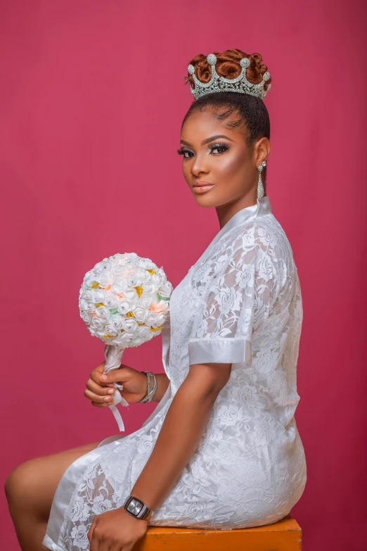 a beautiful young woman sitting on top of a stool holding a white bouquet