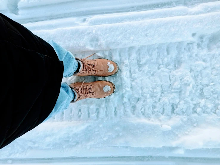 two person wearing black shoes standing on a snow covered area