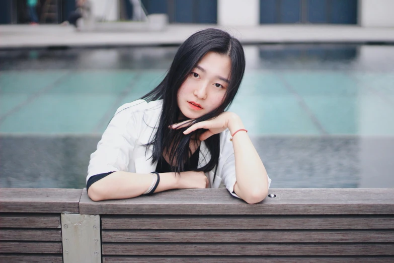 a girl in white shirt leaning on wooden bench