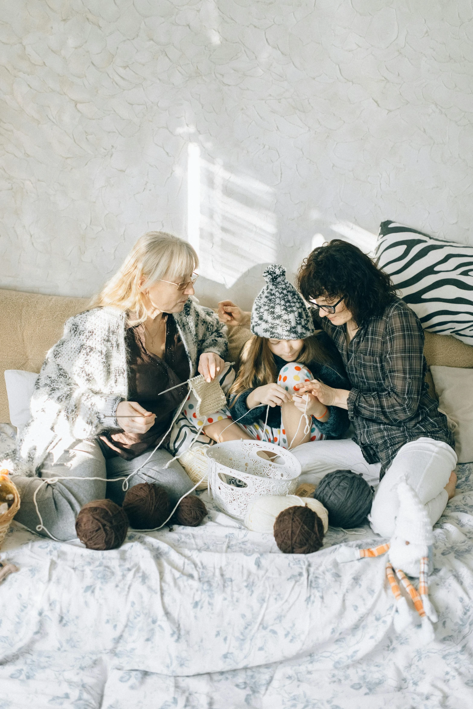 two women and a baby sitting in a bed together