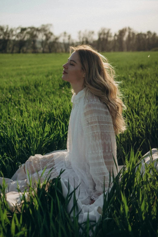 the woman is in white sitting in the grass