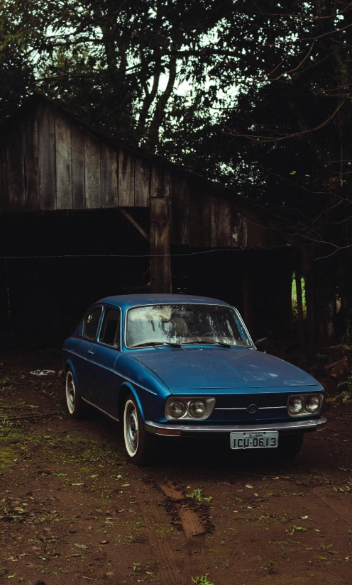 a small blue car parked next to a wooden structure