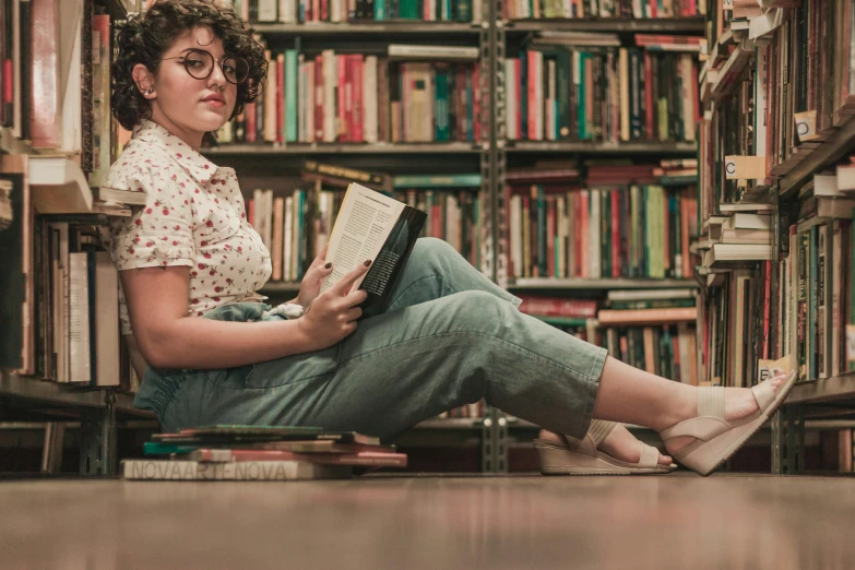 a woman sits in front of a bookshelf and reades