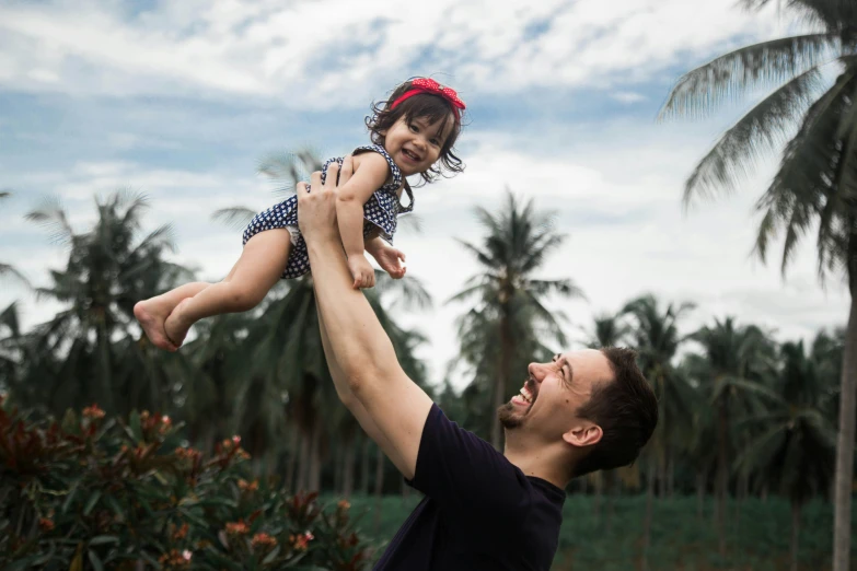 the man holds the little girl on his arm