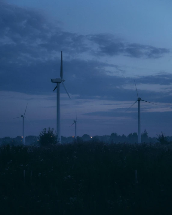 several wind mills sit in the distance against the blue cloudy sky