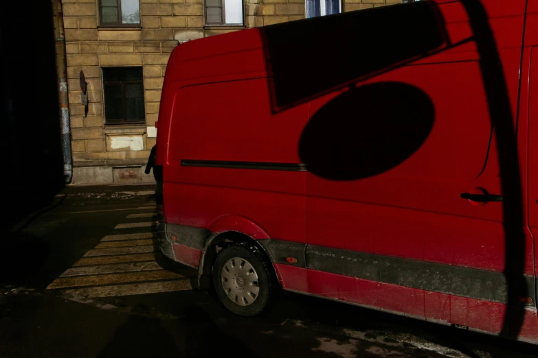 a red van with some windows in the street