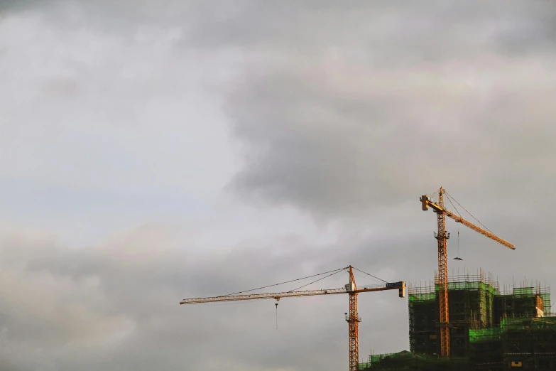 cranes against a dark sky and buildings under construction