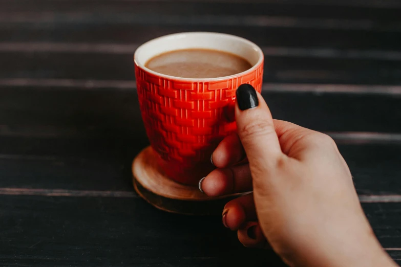 a woman holding a cup of coffee on top of a table