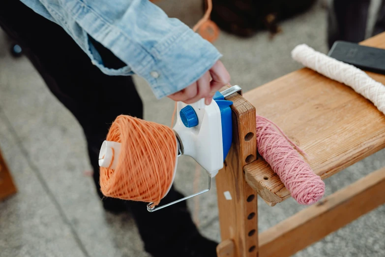 the person is making a string art project on a stool