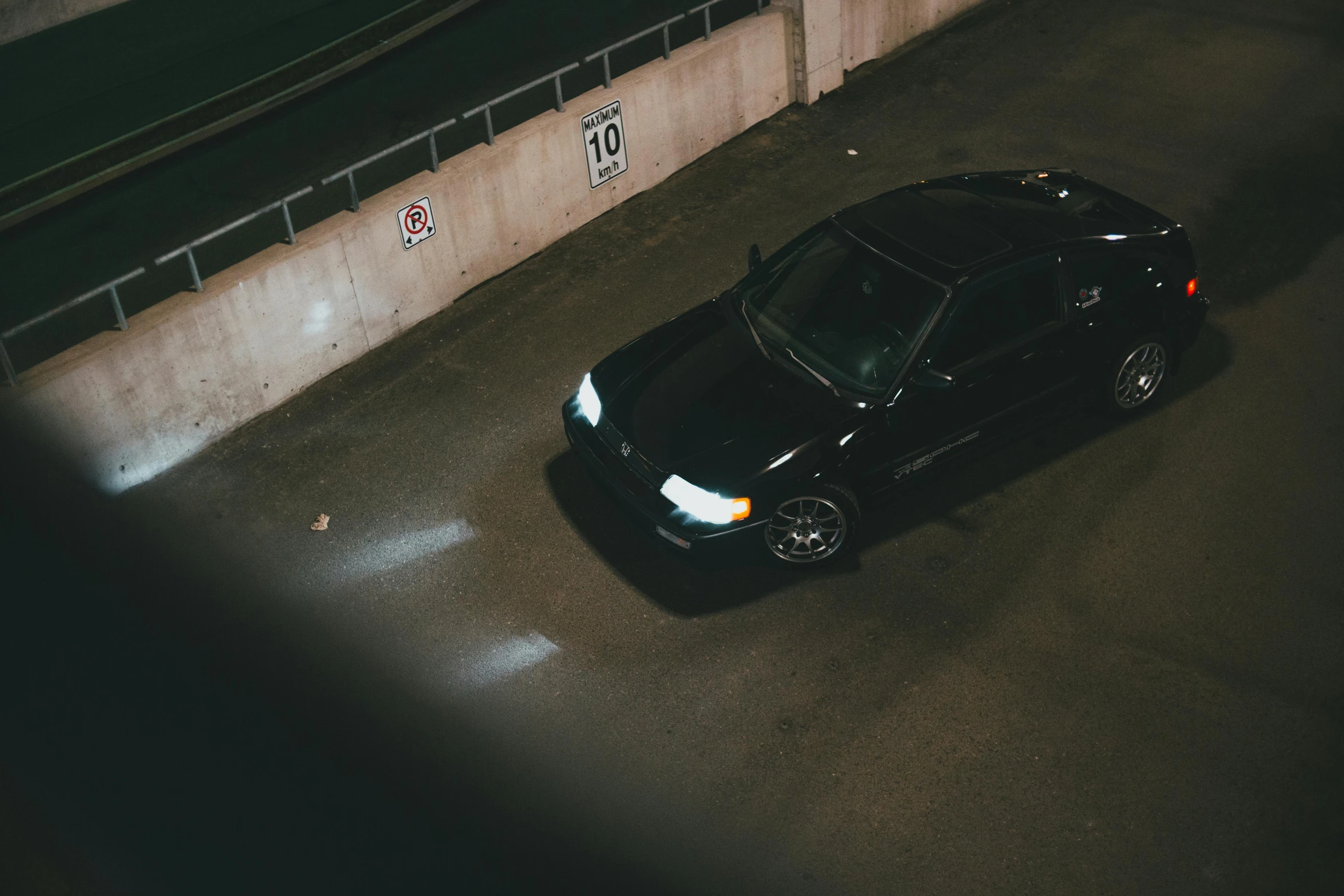 black car parked in dark parking lot at night