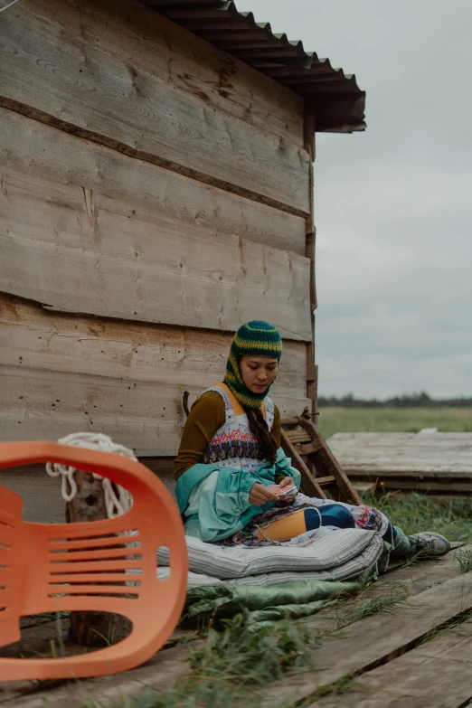 the woman is sitting on the wood floor beside her tent