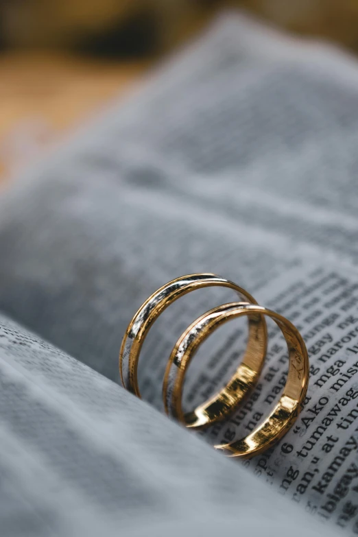 three gold rings sit on top of an open book