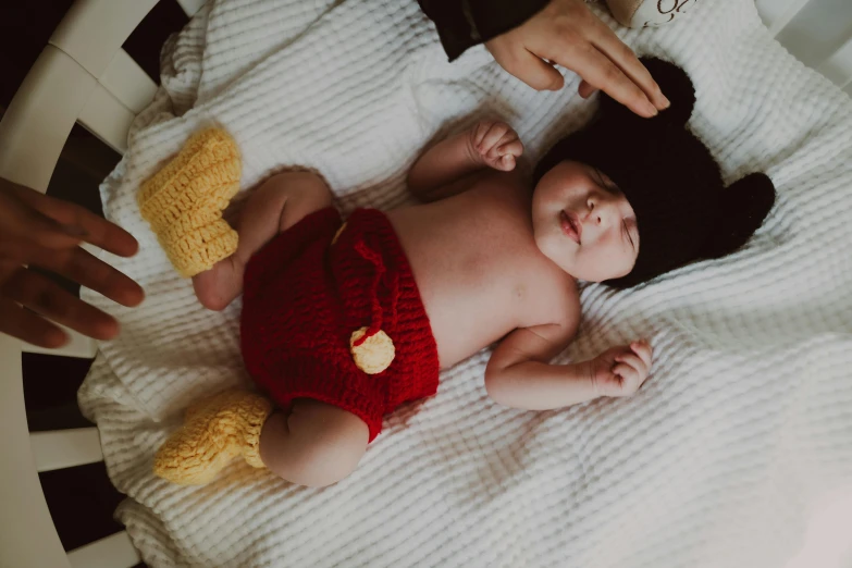 a baby lying on a white blanket in front of another baby