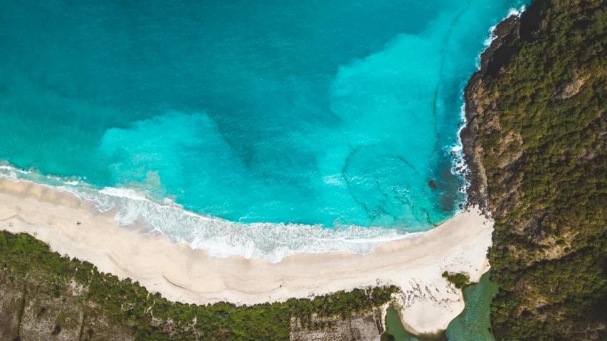 a blue and white beach near some hills