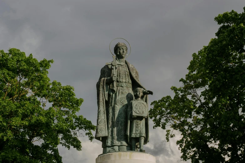 a statue with trees surrounding it on a cloudy day