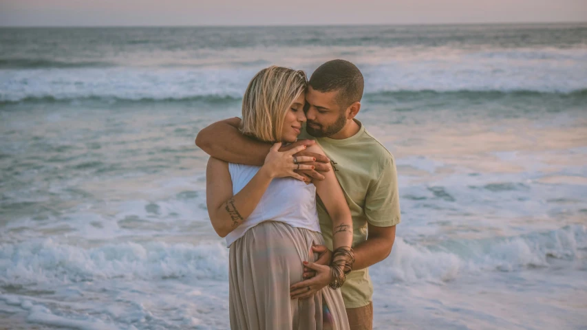 an engaged couple cuddling near the ocean