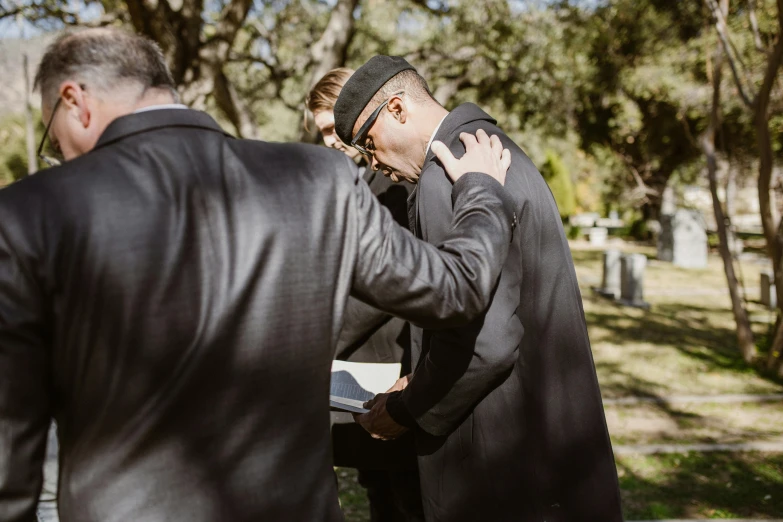 a man in a suit is covering his face with another mans arms