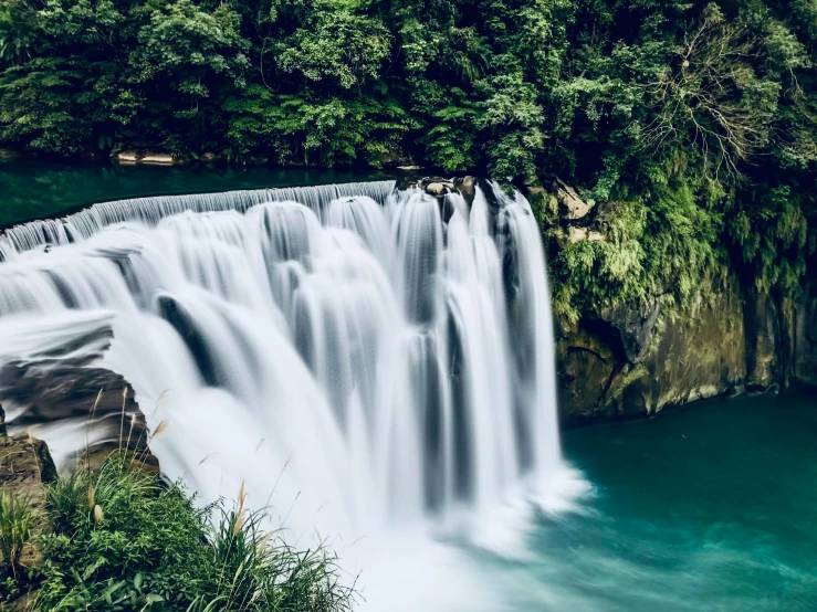 a waterfall is in the water near some trees