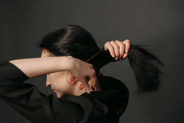 an asian woman holding up her hair with both hands