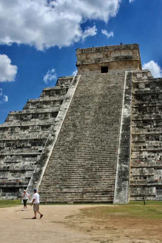 a couple of people walking in front of a large pyramid