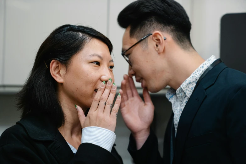 two asian business people holding their hands up to a joke