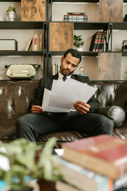 a man in suit sitting on the couch while reading